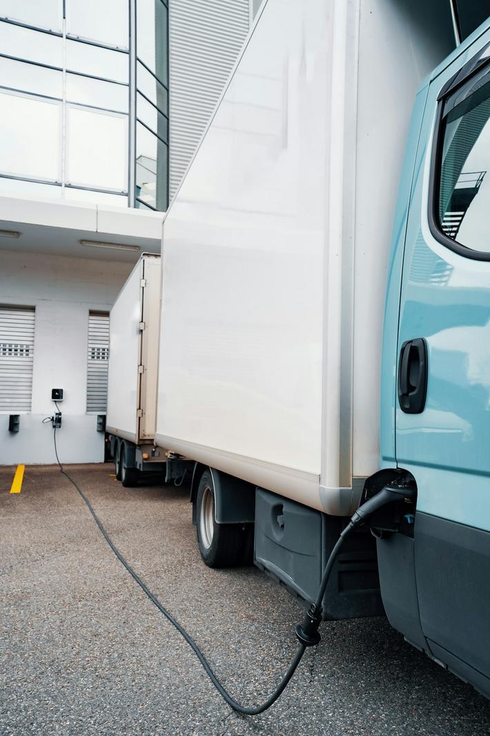 Camion poids lourd électrique en cours de recharge à une station moderne, illustrant la transition énergétique dans le transport routier by neomproject.fr